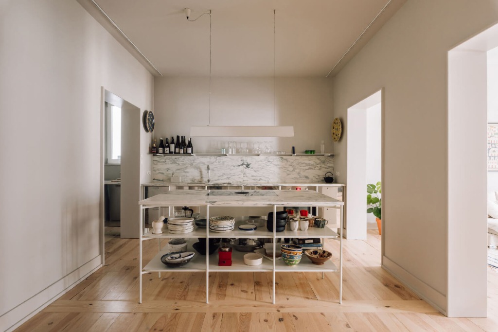 interior luminoso de apartamento com chão de madeira clra e uma estante a dividir o espaço de estar e a cozinha